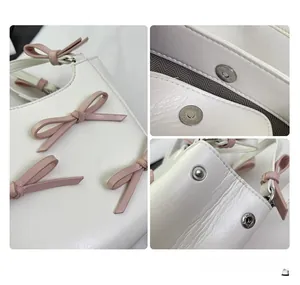 Detail showing pink ribbon bow, magnetic closure, and side rivet on cream crossbody bag