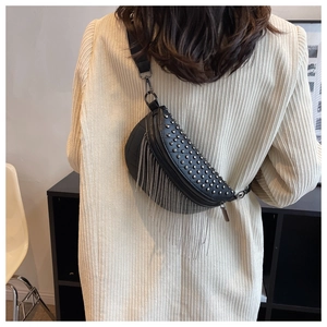 Detail of black leather crescent bag with silver rivets and long chain tassels worn by a model