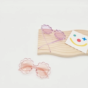 Detailed overhead view of flower-shaped children's sunglasses in pink and lilac colors