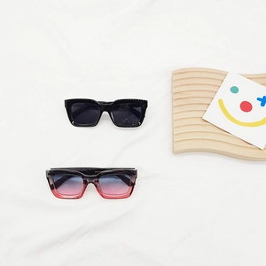 Ensemble de lunettes de soleil carrées noires et dégradées sur un élégant fond en tissu blanc