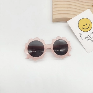 Close-up of flower shaped kids sunglasses in translucent pink with dark lenses