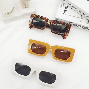 Modern square frame sunglasses in tortoiseshell, mustard, and ivory finishes on white cloth