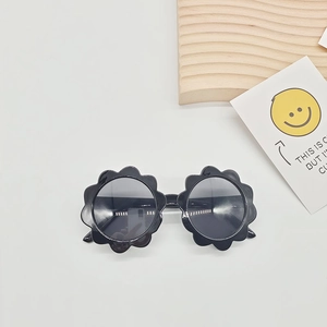 Detail shot of black flower shaped kids sunglasses with dark UV lenses on a clean background
