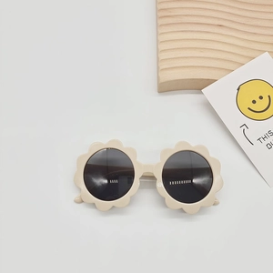 Detailed macro view of beige flower-shaped kids sunglasses with black UV protection lenses