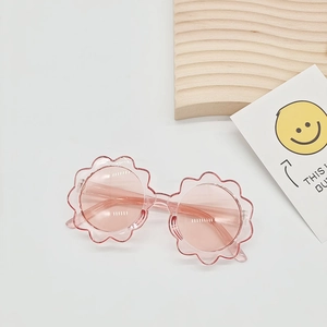 Detail of pink flower-shaped sunglasses for kids with transparent frames and UV lenses