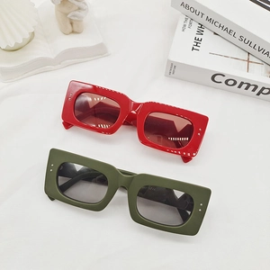 Retro wide rectangular sunglasses in red and olive green on a white fabric background
