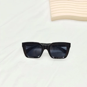 Vue à plat de lunettes de soleil carrées noires classiques sur tissu blanc élégant