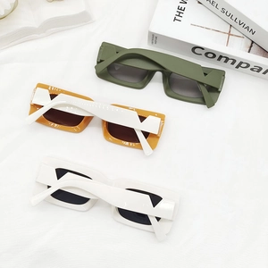 Three pairs of vintage rectangle sunglasses in green, orange and white on white fabric