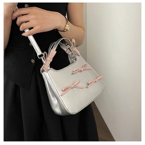 Detail of silver crossbody bag with five pink bow accents on premium PU leather finish