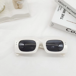 Detail of off-white rectangle sunglasses with dark grey lenses on white textured fabric