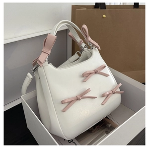 Detailed shot of white PU leather bag featuring pink bows and an adjustable strap
