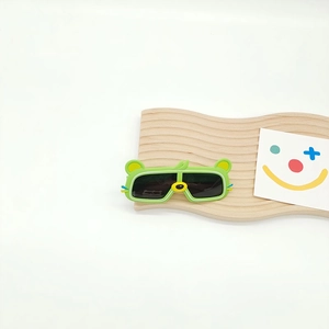 Détail de lunettes de soleil enfant ours vert avec oreilles jaunes sur présentoir en bois