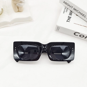 Detail of black rectangular sunglasses with silver studs on a modern white background