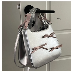 Close-up of silver crossbody bag with pink 3D bows hanging on a door handle