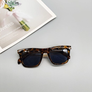 Flat lay of retro tortoiseshell square sunglasses on a minimalist magazine backdrop