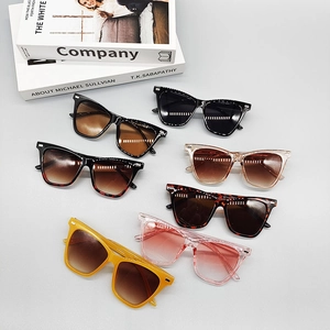 Close-up showing seven stylish colors of rectangular frame sunglasses stacked on books