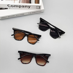Three pairs of vintage square sunglasses with rice-nail accents on a grey background
