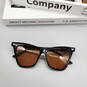 Detail view of square black sunglasses with brown lenses and silver hinge accents