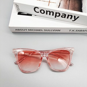 Detail shot of square pink transparent frame sunglasses with gradient lenses on books