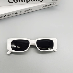 Detailed top view of white rectangular sunglasses with dark lenses on fashion books