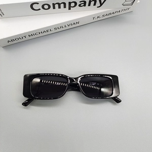 Close-up of vintage black rectangular sunglasses laid on decorative books in a studio setting