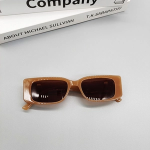 Detail view of rectangular caramel translucent frame sunglasses with dark lenses on books