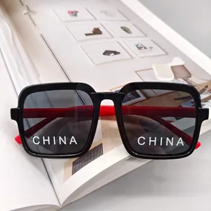 Detail of kids square sunglasses with black frame and red temples on art magazine background
