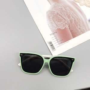 Détail de lunettes de soleil carrées enfant vert menthe avec branches blanches stylées