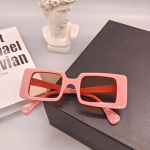 Gros plan de lunettes de soleil roses rectangulaires sur un présentoir noir texturé
