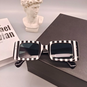 Détail de lunettes de soleil rectangulaires zébrées posées sur un coffret noir