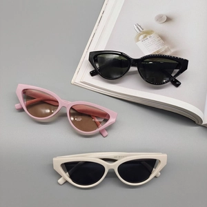 Trendy cat-eye triangular sunglasses in black, pink, and off-white on a fashion magazine