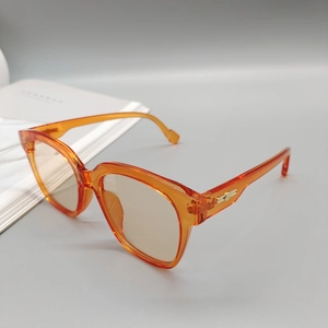 Detail shot of orange translucent oval sunglasses with golden metal hinge decorations