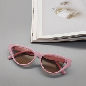 Detailed view of pink cat-eye sunglasses frames and dark lenses on a fashion magazine