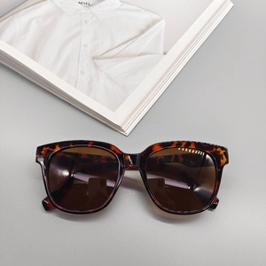 Detail view of tortoiseshell oval sunglasses with dark brown lenses on a fashion magazine