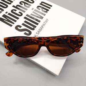 Detail of dark tortoiseshell cat-eye sunglasses with metal rivets and brown lenses