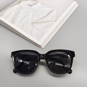 Close-up of glossy black oversized sunglasses with dark lenses on a minimalist background