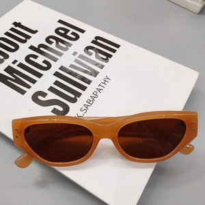 Close-up of retro cat-eye sunglasses with translucent orange frame and silver rivets