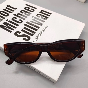 Detail of tortoiseshell cat-eye sunglasses with metal dots on a white book