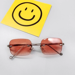 Détail de lunettes de soleil enfant sans monture avec verres roses dégradés et métal