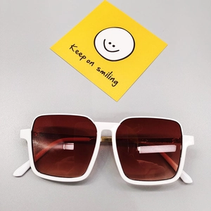 Détail de lunettes de soleil carrées enfant blanches avec verres dégradés bruns et charnière or
