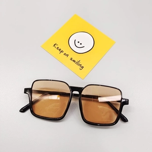 Lunettes soleil enfant monture noire verres orange avec carte décorative souriante
