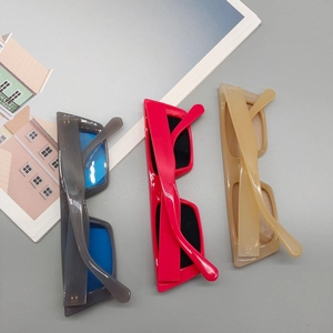 Trois lunettes de soleil rectangulaires rétro en gris transparent, rose et beige sur fond gris