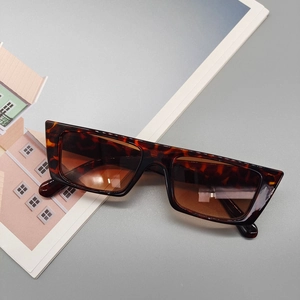 Vue détaillée de lunettes de soleil rectangulaires écaillées avec verres marrons sur un magazine