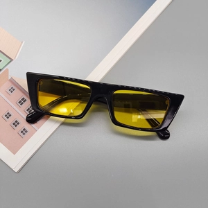 Détail de lunettes de soleil carrées rétro avec monture noire et verres teintés jaunes