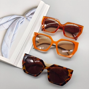 Detailed view of square thick frame sunglasses in amber, orange, and tortoiseshell colors