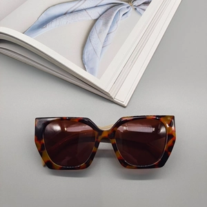 Flat lay of stylish oversized tortoiseshell sunglasses with brown lenses on a magazine