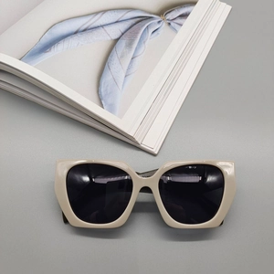 Detail shot of polygon sunglasses with cream frame and dark lenses on a magazine background
