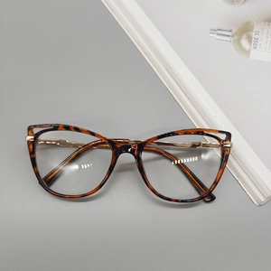 Détail de lunettes œil-de-chat écaille avec branches dorées et charnière évidée