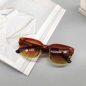 Detail of amber to green gradient square frame sunglasses resting on a fashion magazine