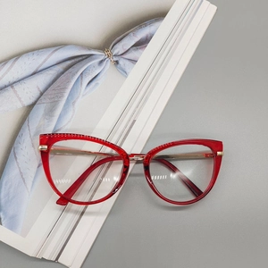 Detail of red cat-eye TR90 glasses with gold metal temples on a magazine backdrop